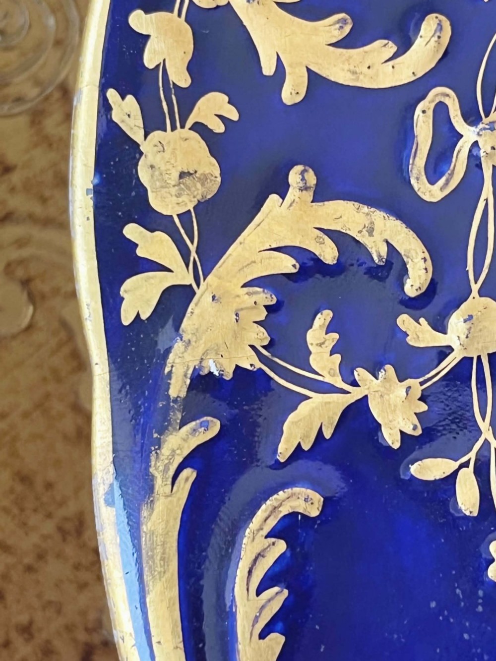 An antique Coalport porcelain dessert plate featuring a central hand-painted floral bouquet surrounded by a rich cobalt blue rim decorated with ornate gold gilding. View XII