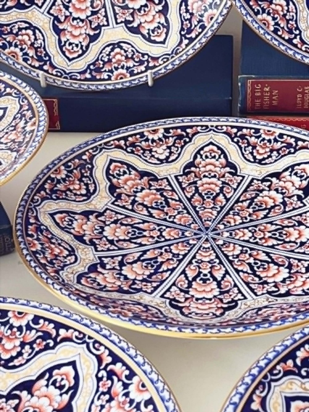 A seven-piece porcelain dessert service featuring intricate cobalt blue, terracotta, and gold geometric star patterns, comprising six plates and a comport. View III
