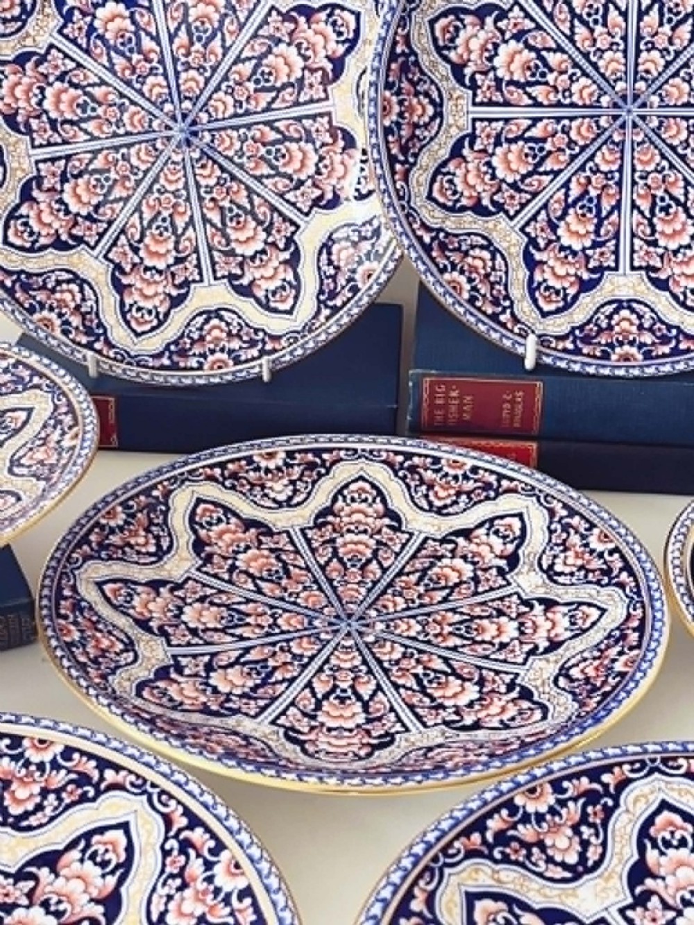 A seven-piece porcelain dessert service featuring intricate cobalt blue, terracotta, and gold geometric star patterns, comprising six plates and a comport. View IV