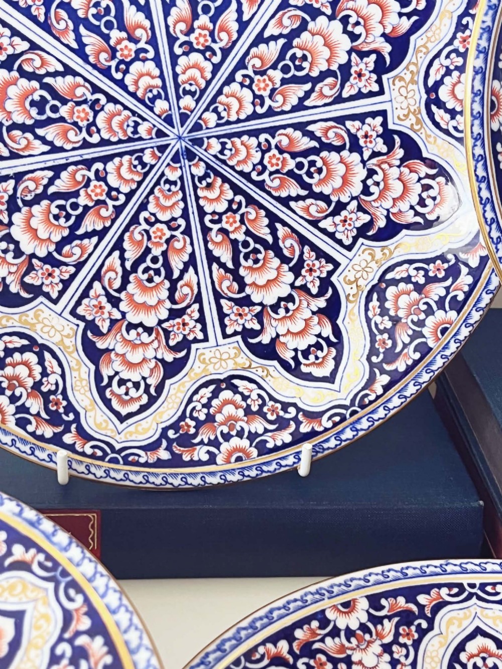 A seven-piece porcelain dessert service featuring intricate cobalt blue, terracotta, and gold geometric star patterns, comprising six plates and a comport. View VI