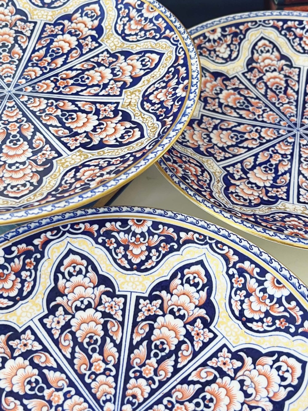 A seven-piece porcelain dessert service featuring intricate cobalt blue, terracotta, and gold geometric star patterns, comprising six plates and a comport. View VIII