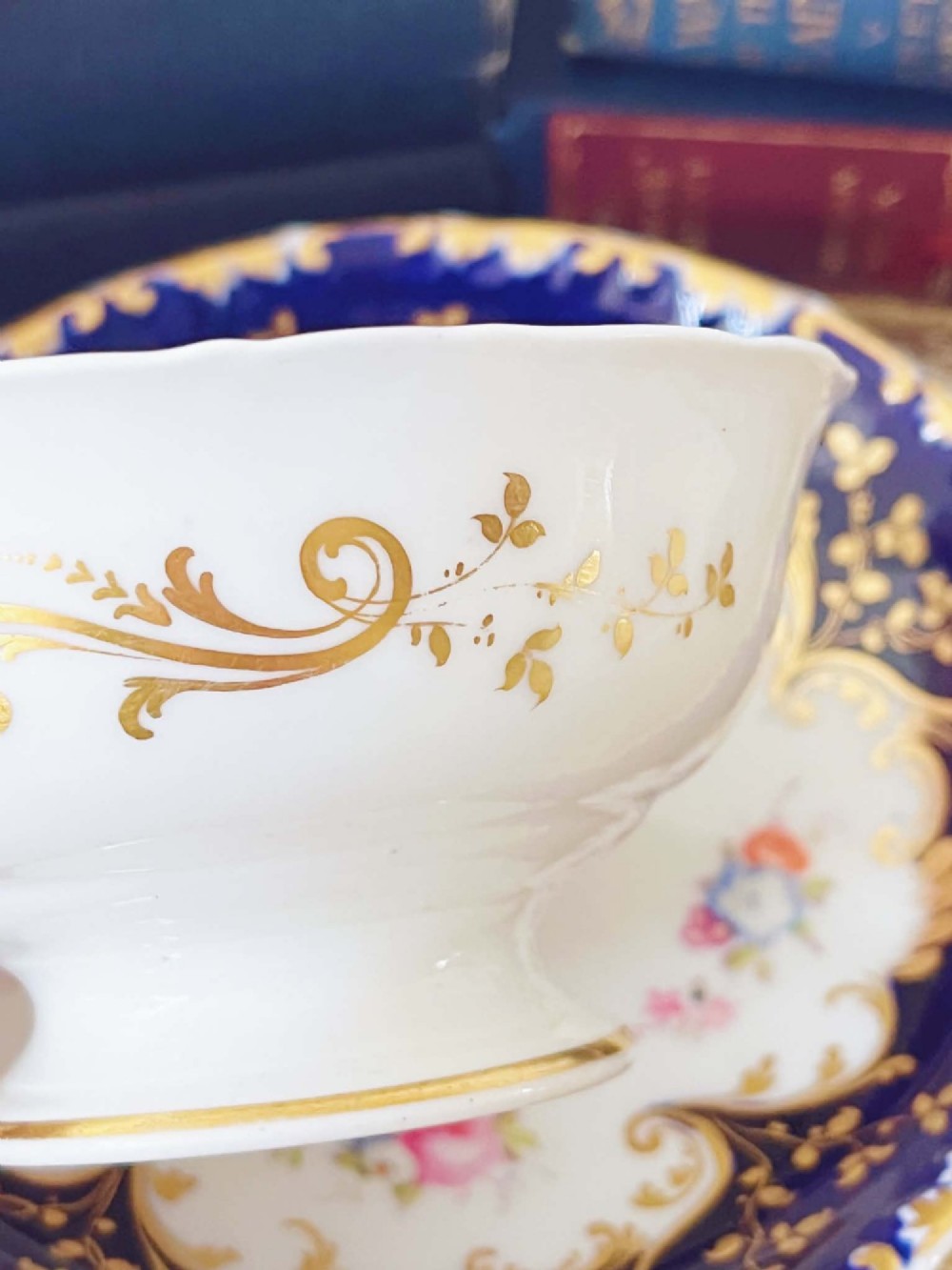 An antique bone china teacup and saucer featuring cobalt blue borders with gold scrollwork and hand-painted floral centres. View VII