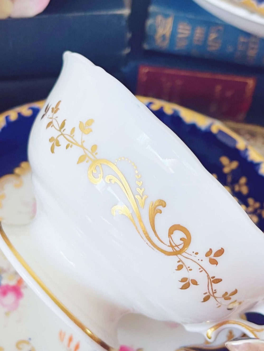 An antique bone china teacup and saucer featuring cobalt blue borders with gold scrollwork and hand-painted floral centres. View VIII