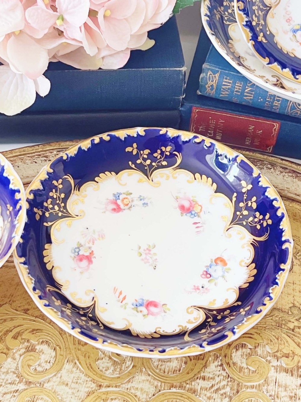 An antique bone china teacup and saucer featuring cobalt blue borders with gold scrollwork and hand-painted floral centres. View IX