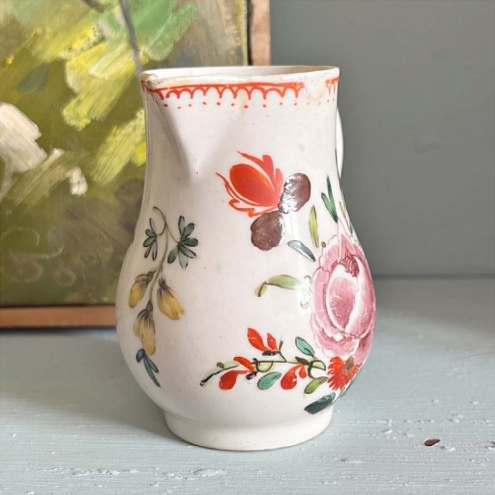 An eighteenth-century Bow soft-paste porcelain sparrowbeak cream jug hand-painted with polychrome floral sprigs and a red painted border. View V