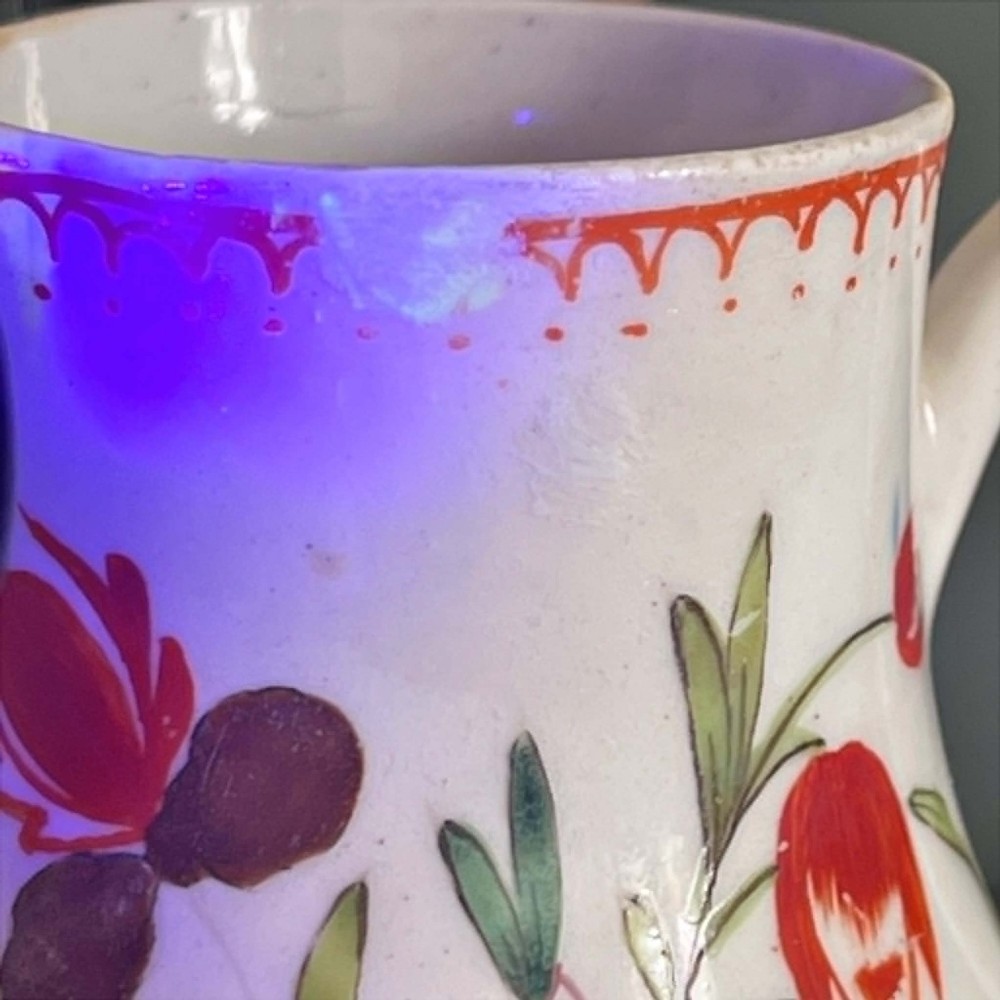 An eighteenth-century Bow soft-paste porcelain sparrowbeak cream jug hand-painted with polychrome floral sprigs and a red painted border. View XI