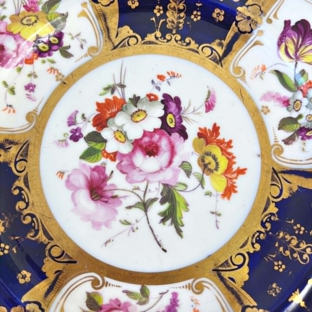 An early nineteenth-century Samuel Alcock porcelain dessert plate featuring a cobalt blue ground, intricate gilt scrolling, and hand-painted floral cartouches. View IX
