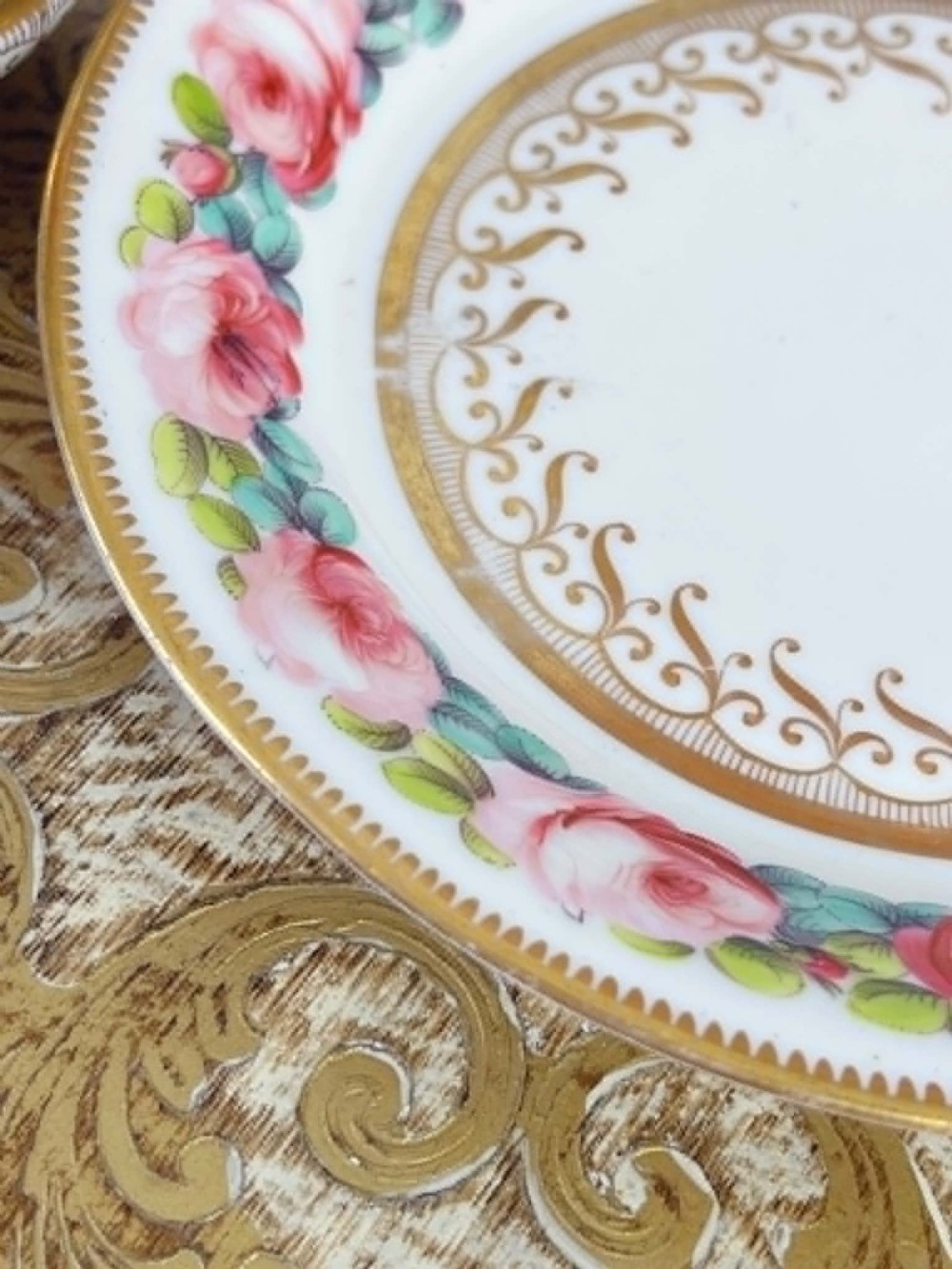 An antique porcelain teacup and matching saucer featuring hand-painted pink cabbage roses, green leaves, and gold scroll decorations. View VI