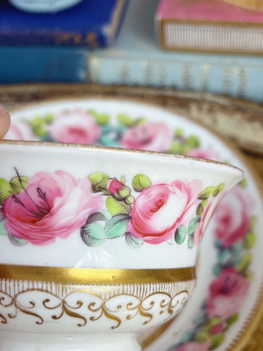 An antique porcelain teacup and matching saucer featuring hand-painted pink cabbage roses, green leaves, and gold scroll decorations. View VIII