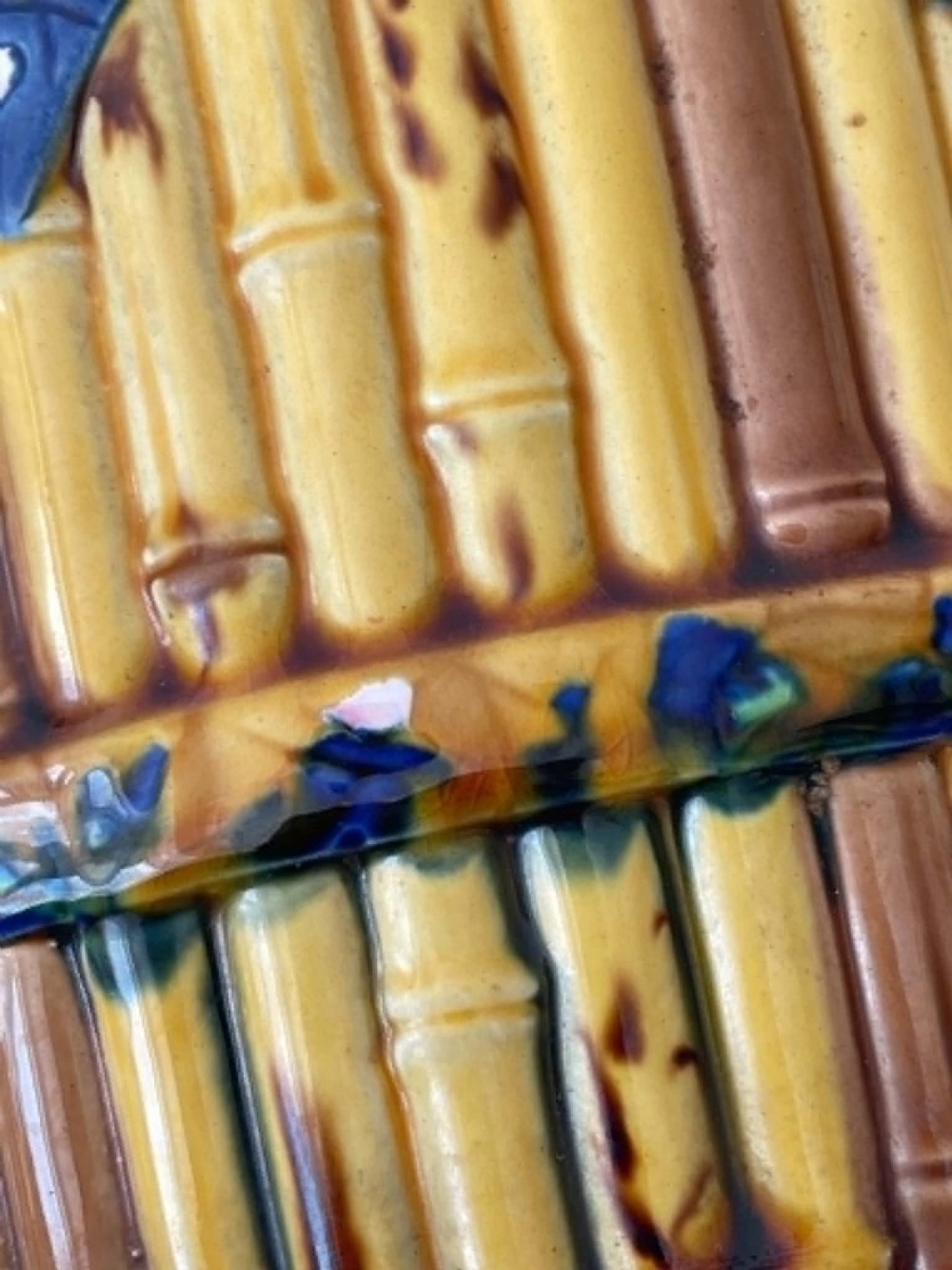 A cylindrical Victorian majolica jardiniere decorated with a moulded bamboo cane pattern in yellow and brown tones, wrapped with a blue ribbon tied in a bow. View X