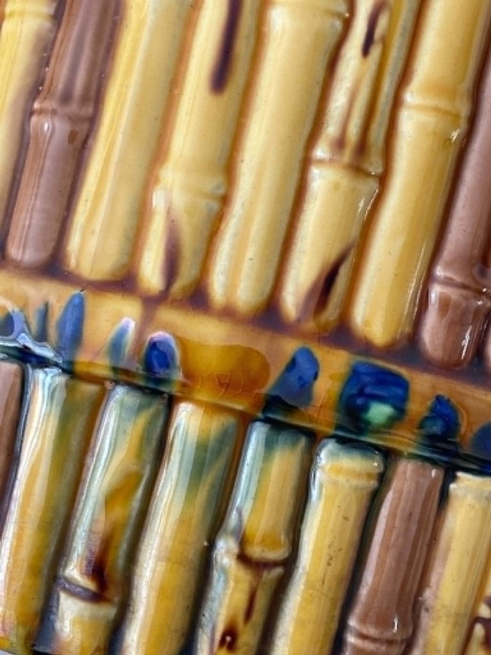 A cylindrical Victorian majolica jardiniere decorated with a moulded bamboo cane pattern in yellow and brown tones, wrapped with a blue ribbon tied in a bow. View XI