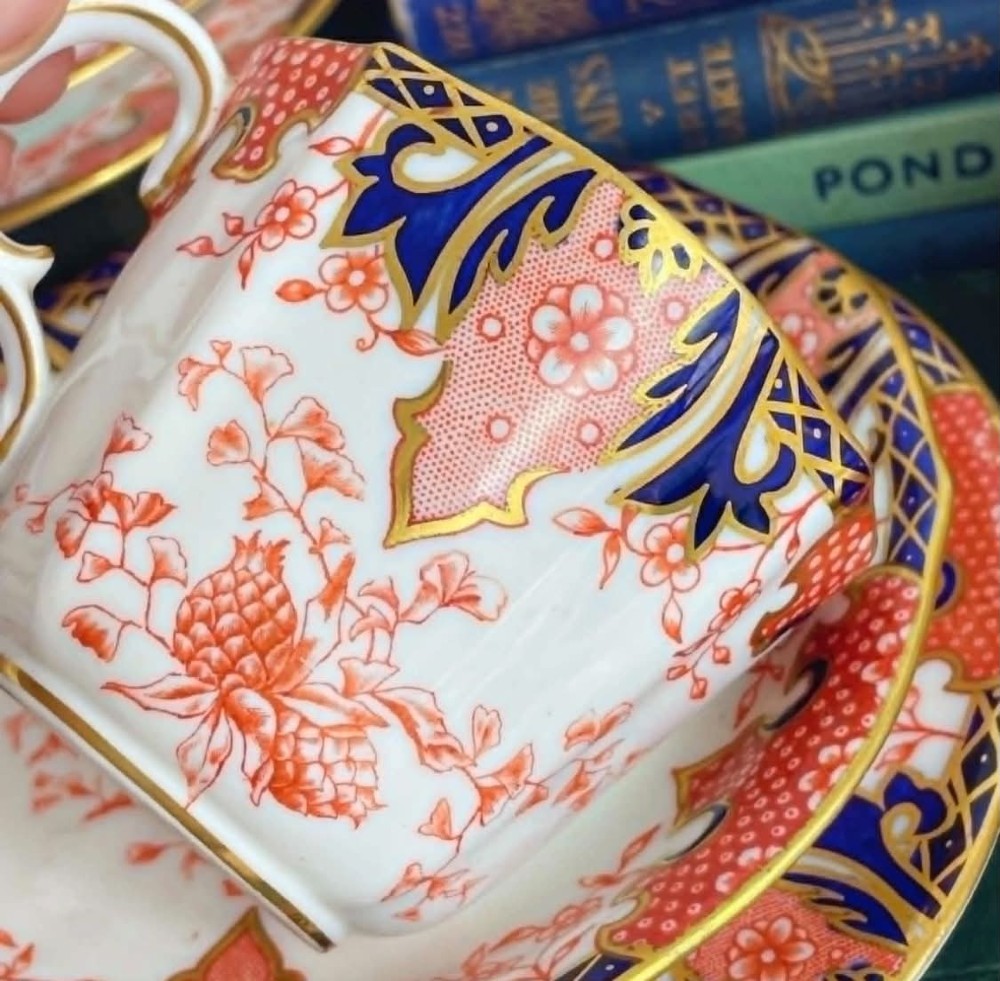 An antique Royal Crown Derby bone china tea set featuring iron red and cobalt blue foliage motifs with gold gilding across cups, saucers, and a cream pitcher. View VI