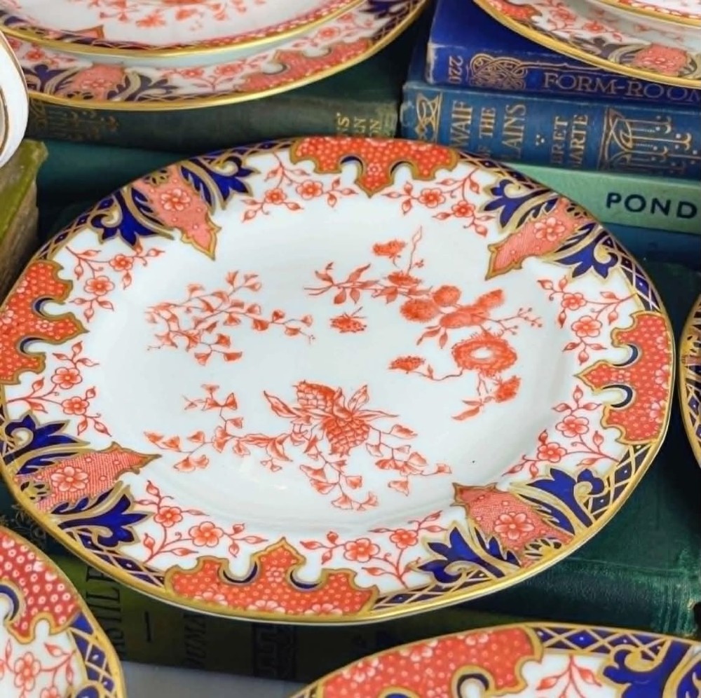 An antique Royal Crown Derby bone china tea set featuring iron red and cobalt blue foliage motifs with gold gilding across cups, saucers, and a cream pitcher. View VIII
