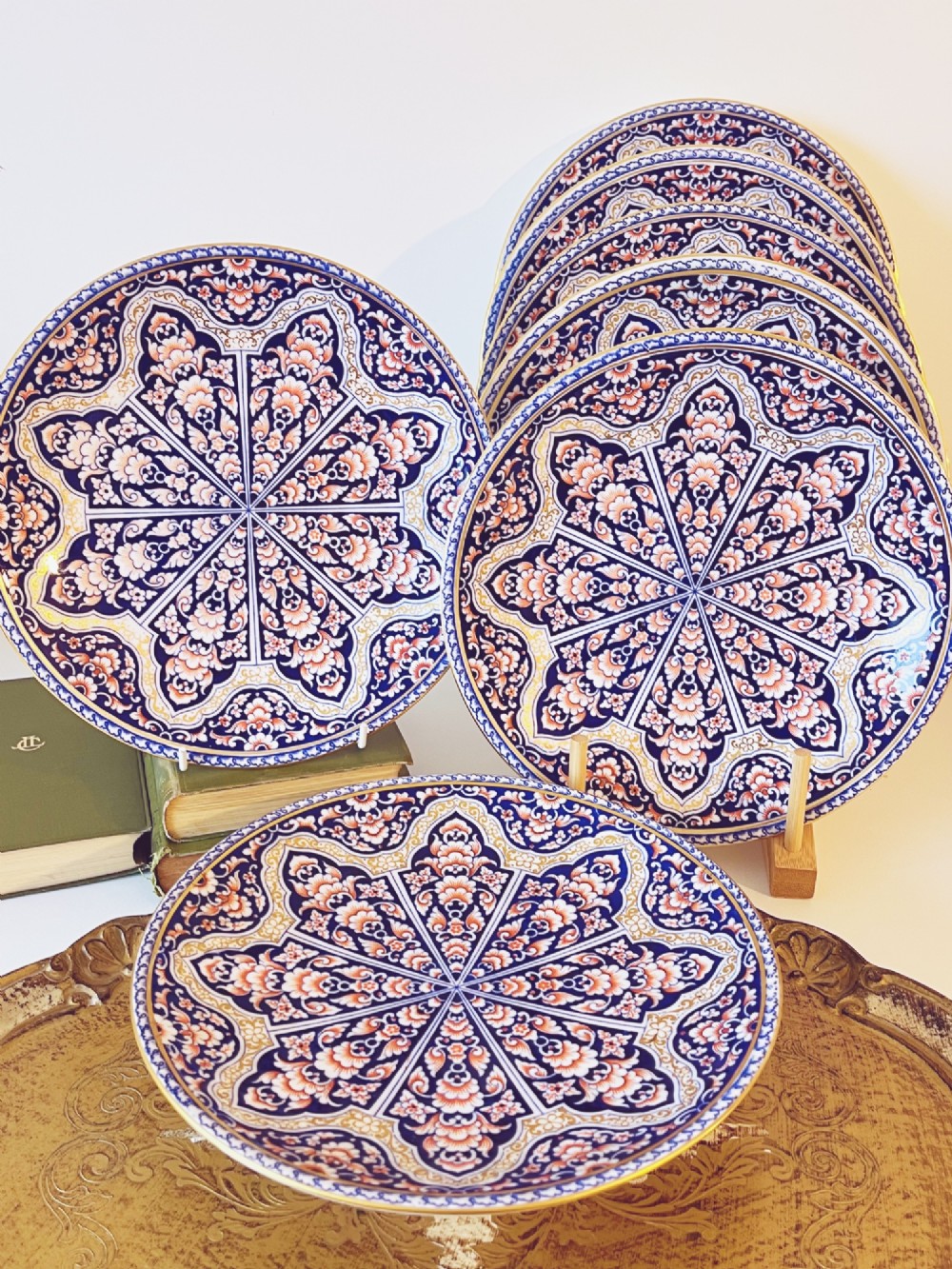 A seven-piece porcelain dessert service featuring intricate cobalt blue, terracotta, and gold geometric star patterns, comprising six plates and a comport.