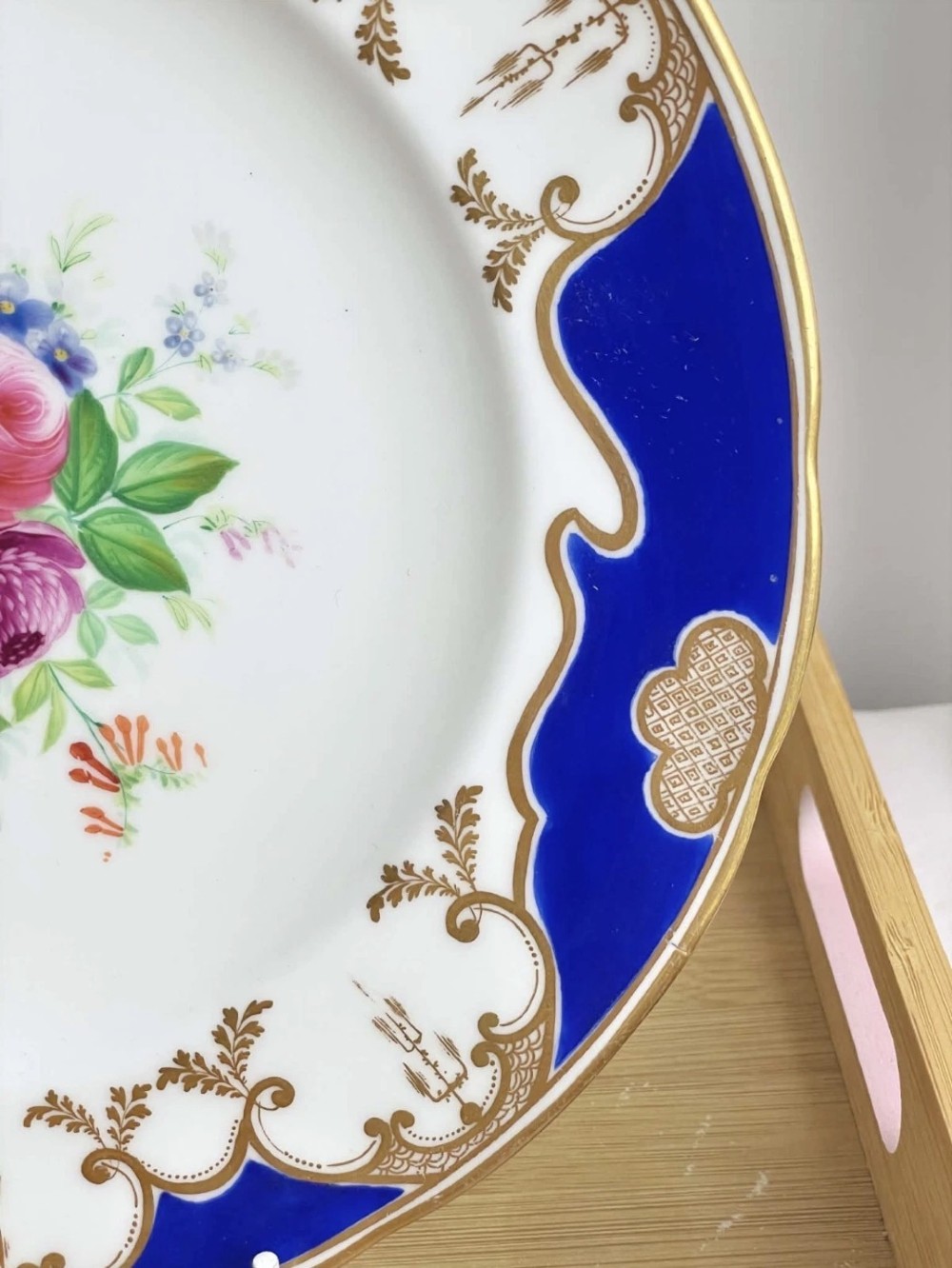 A circular porcelain dessert plate featuring a central hand-painted floral bouquet surrounded by a cobalt blue rim with gilded scrollwork. View III