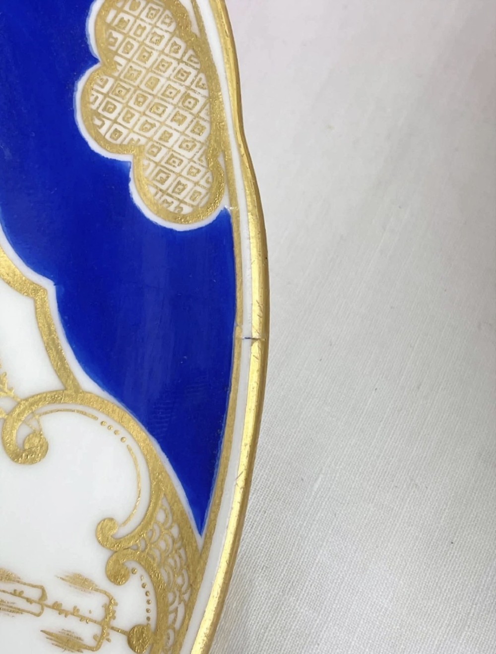 A circular porcelain dessert plate featuring a central hand-painted floral bouquet surrounded by a cobalt blue rim with gilded scrollwork. View IX