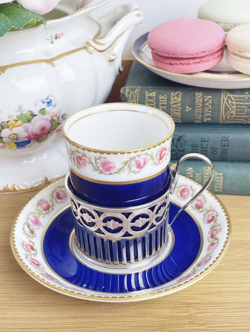 A cobalt blue porcelain coffee can decorated with pink floral swags, set inside a pierced sterling silver holder with a matching saucer. View II