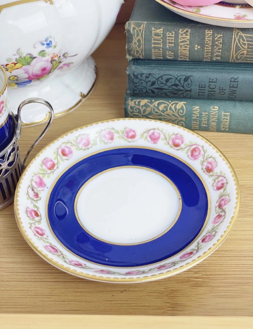 A cobalt blue porcelain coffee can decorated with pink floral swags, set inside a pierced sterling silver holder with a matching saucer. View IV