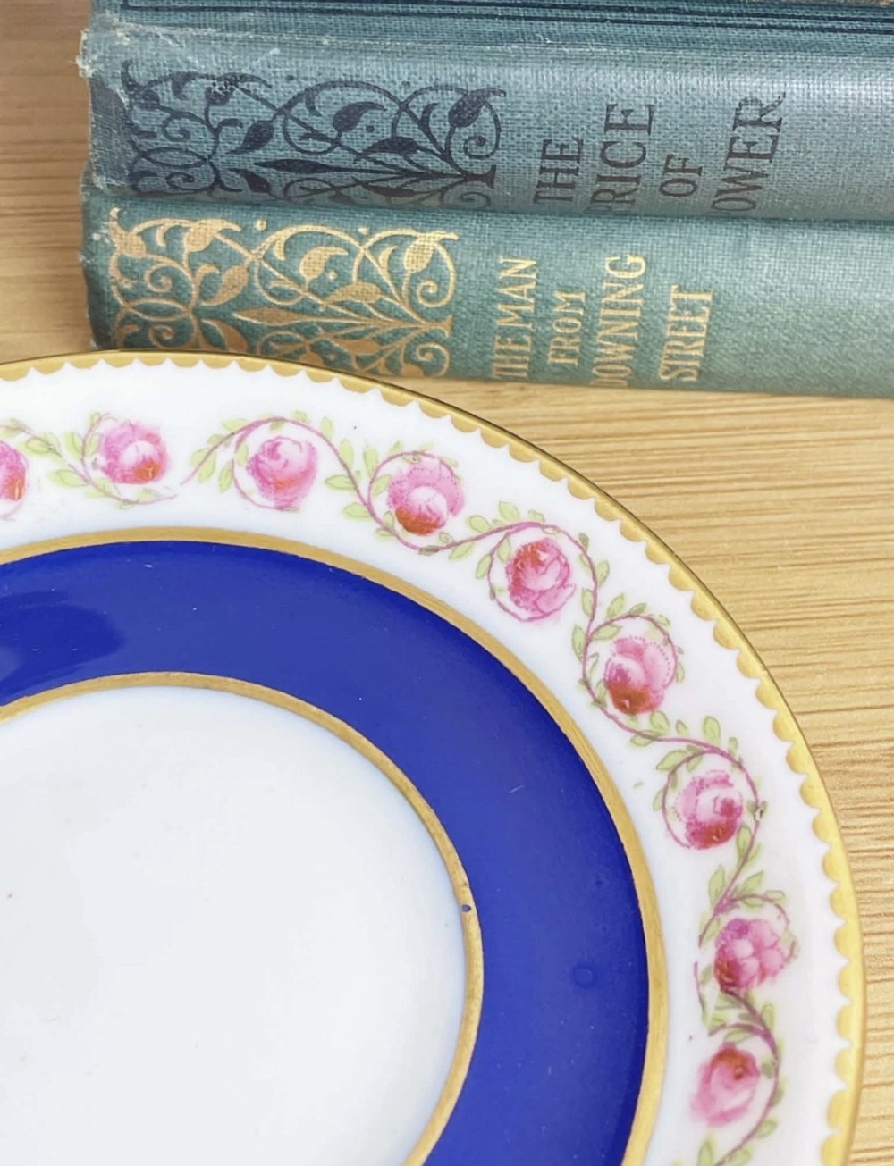 A cobalt blue porcelain coffee can decorated with pink floral swags, set inside a pierced sterling silver holder with a matching saucer. View V