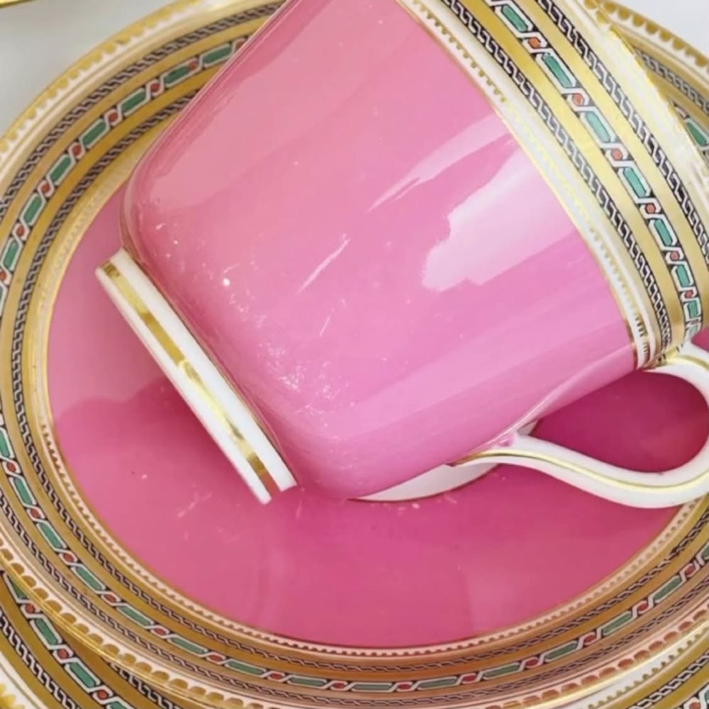 A pink porcelain antique tea trio featuring a teacup, matching saucer, and side plate with gilded geometric borders. View III
