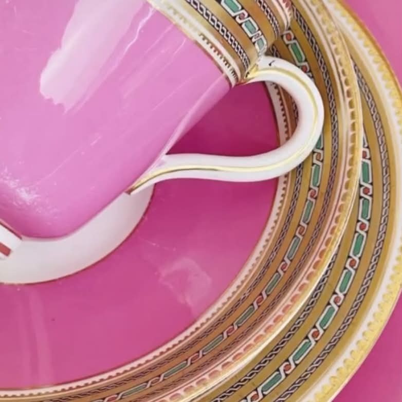 A pink porcelain antique tea trio featuring a teacup, matching saucer, and side plate with gilded geometric borders. View IV