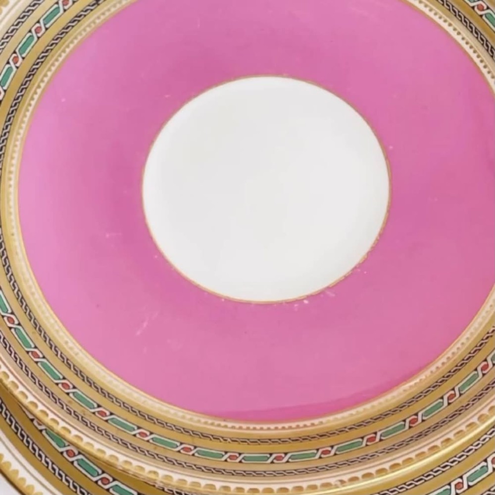 A pink porcelain antique tea trio featuring a teacup, matching saucer, and side plate with gilded geometric borders. View V