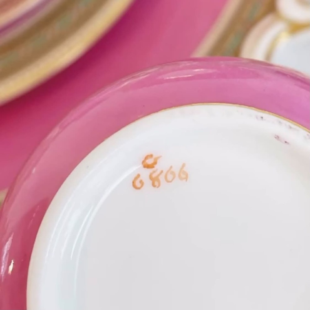 A pink porcelain antique tea trio featuring a teacup, matching saucer, and side plate with gilded geometric borders. View VI