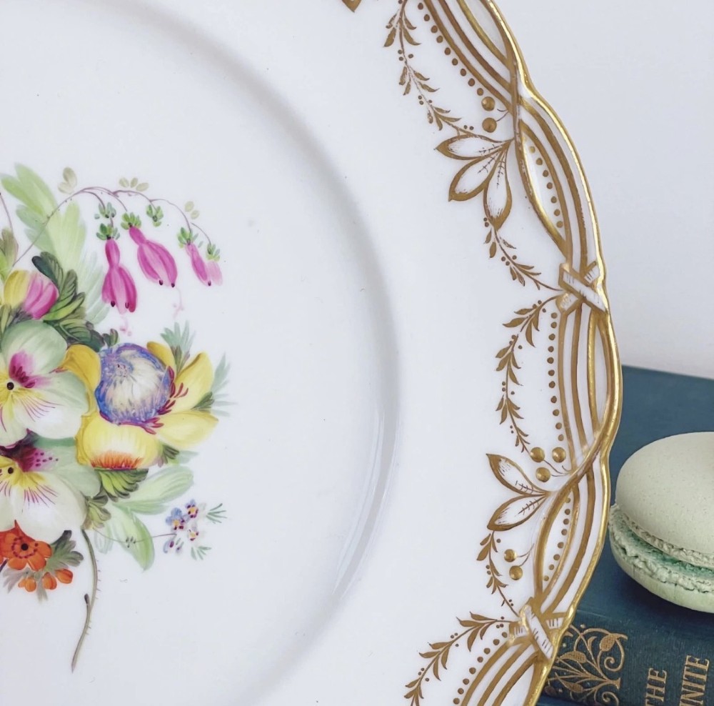 A circular Victorian Coalport porcelain dessert plate featuring a hand-painted central floral motif surrounded by an intricate gilded border. View III