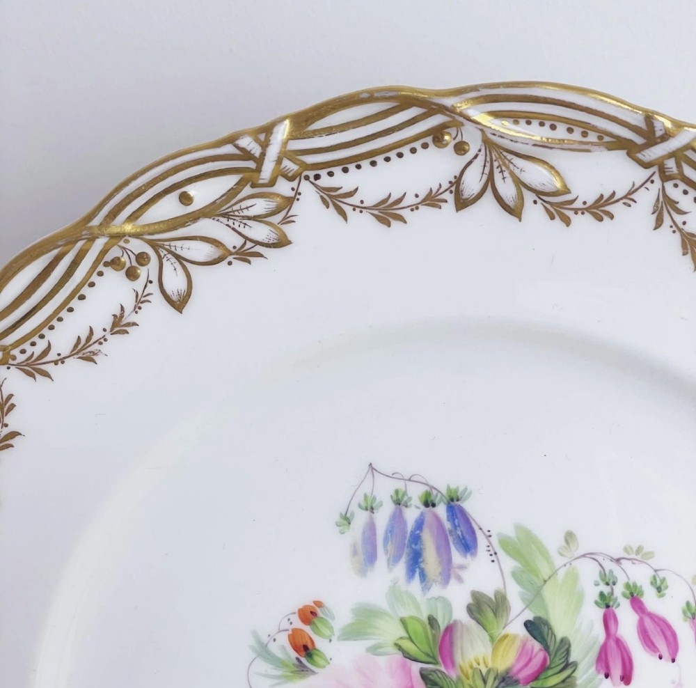 A circular Victorian Coalport porcelain dessert plate featuring a hand-painted central floral motif surrounded by an intricate gilded border. View V