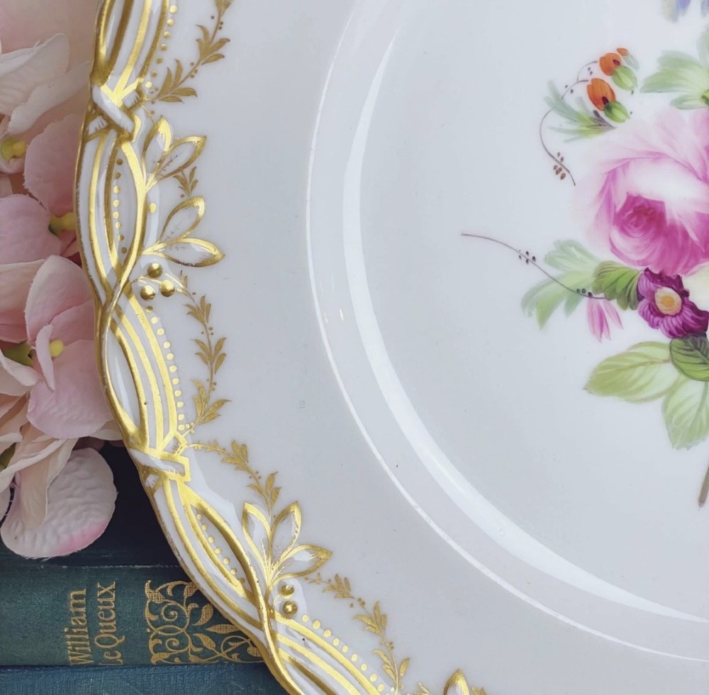 A circular Victorian Coalport porcelain dessert plate featuring a hand-painted central floral motif surrounded by an intricate gilded border. View VII