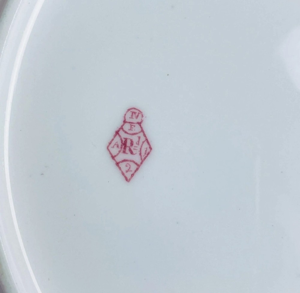 A circular Victorian Coalport porcelain dessert plate featuring a hand-painted central floral motif surrounded by an intricate gilded border. View X