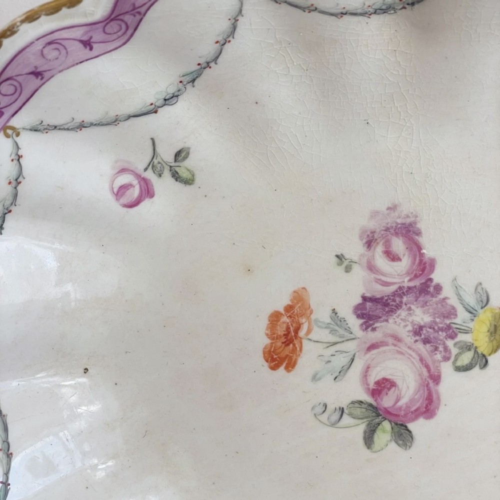 An eighteenth-century oval Derby porcelain serving dish with a scalloped rim, pink scroll border with gilt detailing, and central hand-painted floral spray. View IX