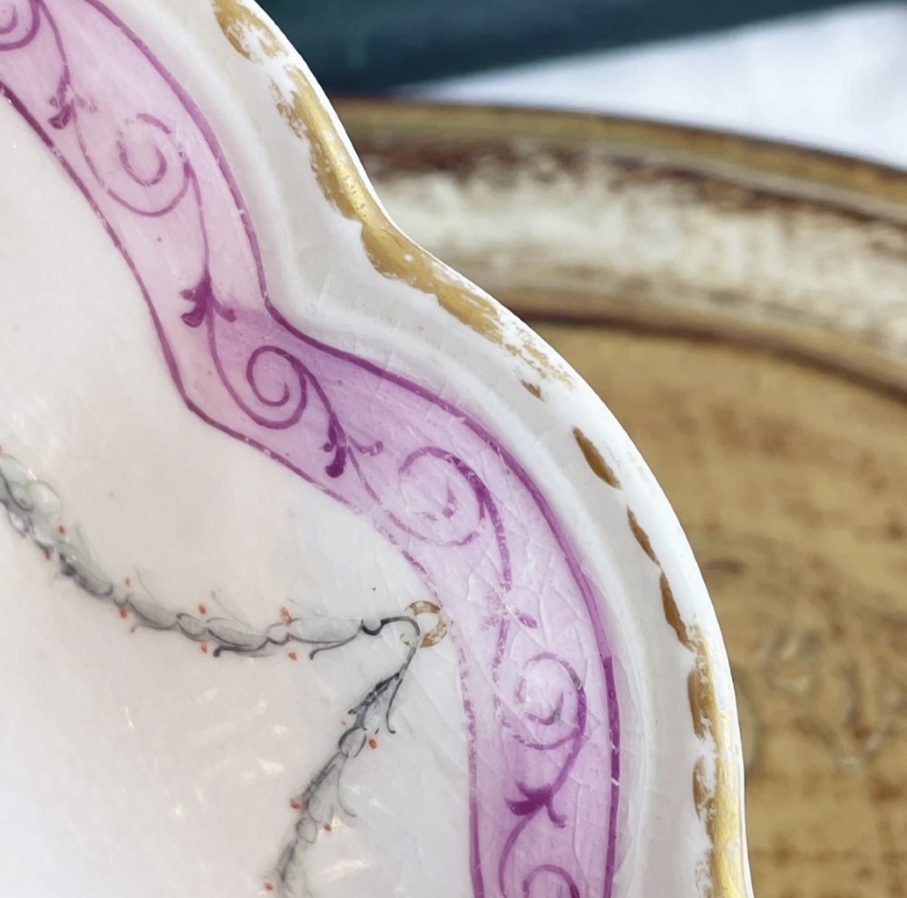 An eighteenth-century oval Derby porcelain serving dish with a scalloped rim, pink scroll border with gilt detailing, and central hand-painted floral spray. View XI