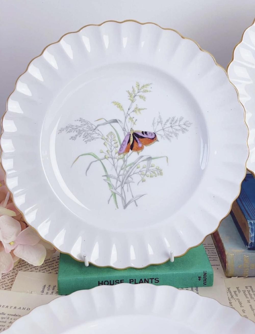 A set of white bone china dessert plates featuring scalloped gilded edges and botanical butterfly illustrations at the centre. View II