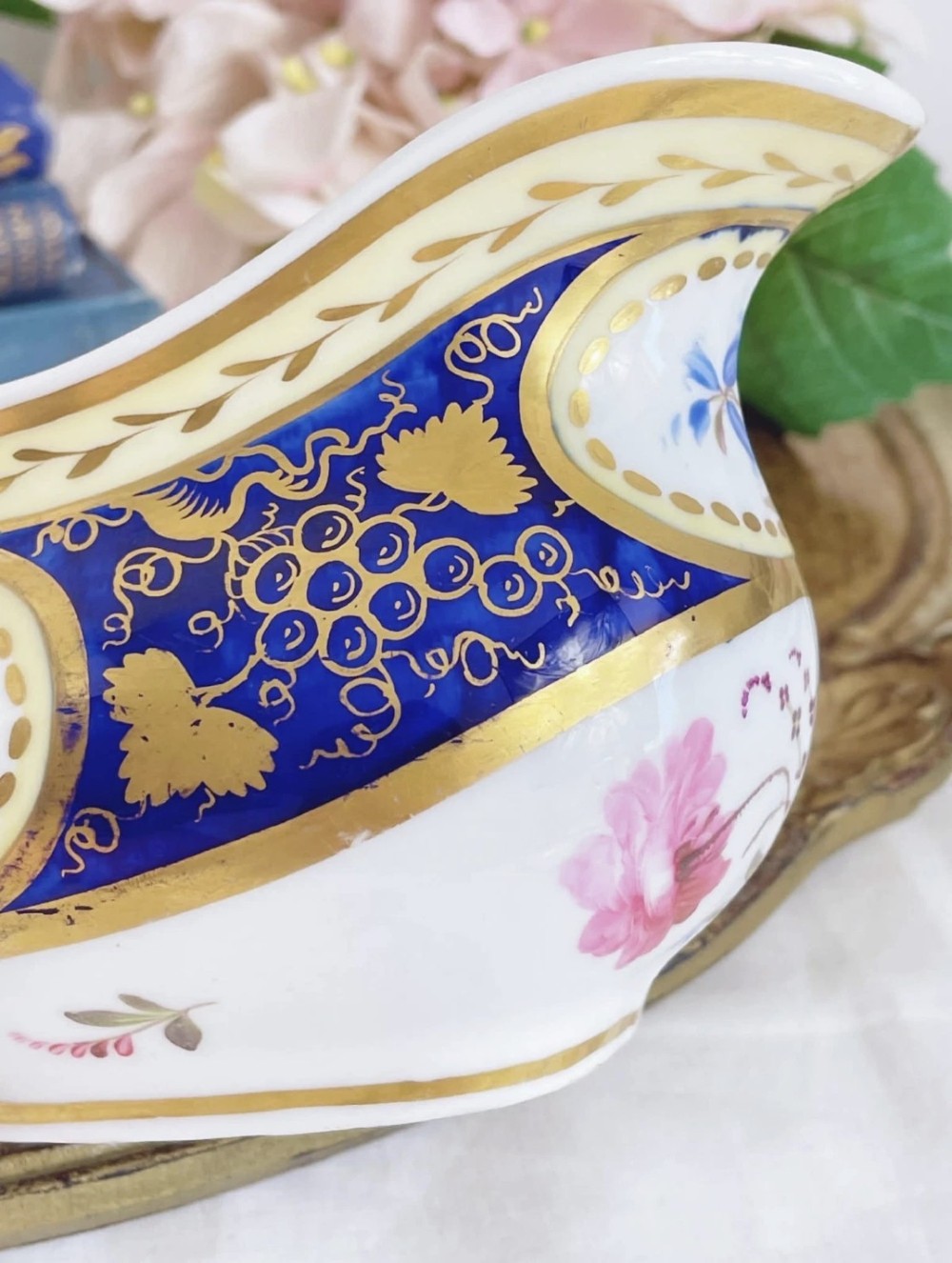 An antique Regency porcelain milk jug decorated with cobalt blue panels, gilt vine details, and hand-painted floral cartouches. View VI
