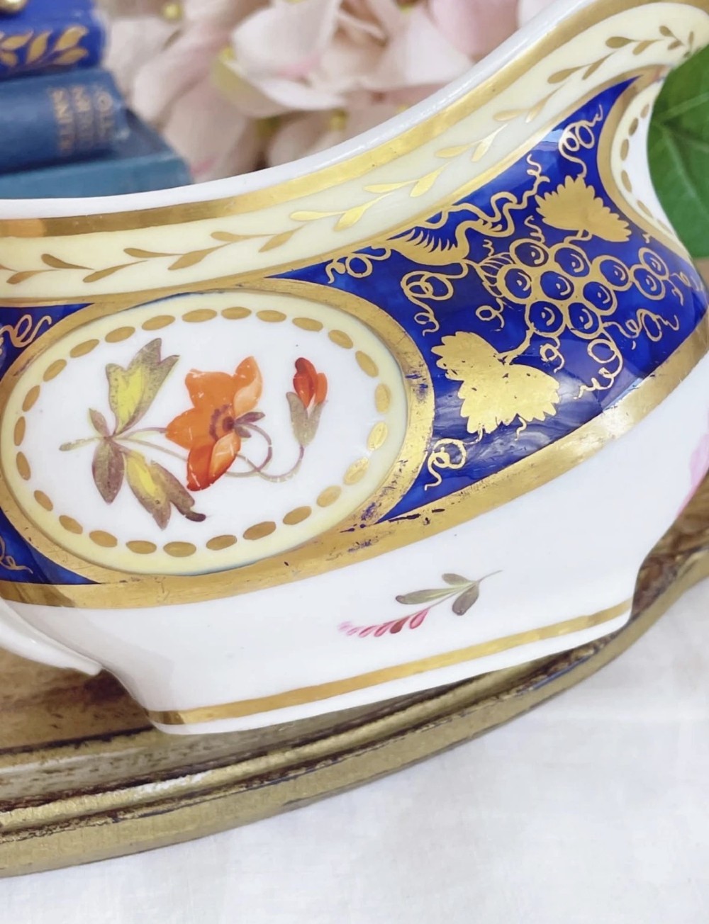An antique Regency porcelain milk jug decorated with cobalt blue panels, gilt vine details, and hand-painted floral cartouches. View VII