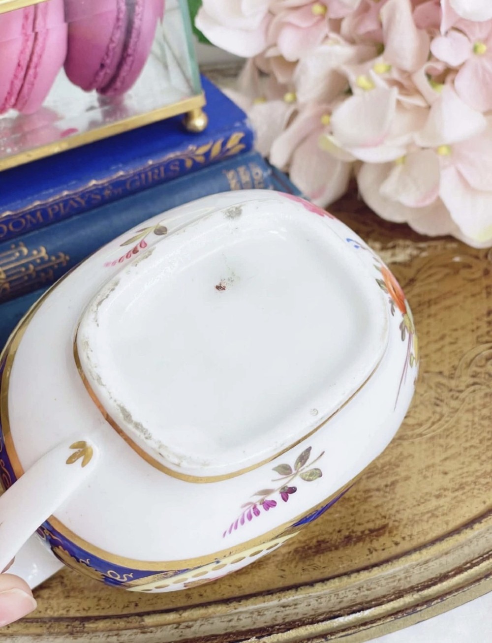 An antique Regency porcelain milk jug decorated with cobalt blue panels, gilt vine details, and hand-painted floral cartouches. View X