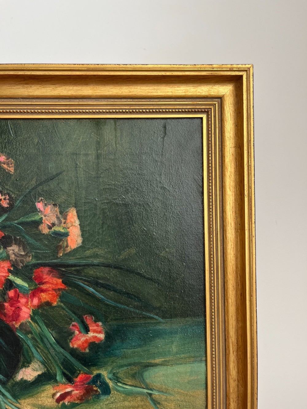 A horizontal oil painting depicting a bouquet of red, pink, yellow, and white carnations in a dark vase, enclosed within a moulded gilt frame. View VI