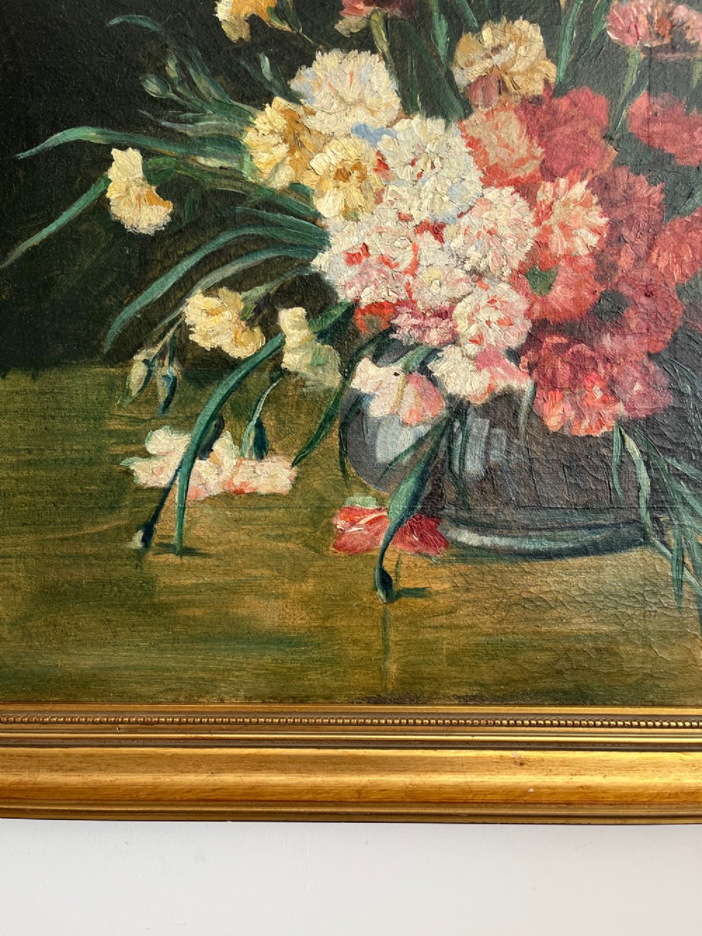A horizontal oil painting depicting a bouquet of red, pink, yellow, and white carnations in a dark vase, enclosed within a moulded gilt frame. View IX