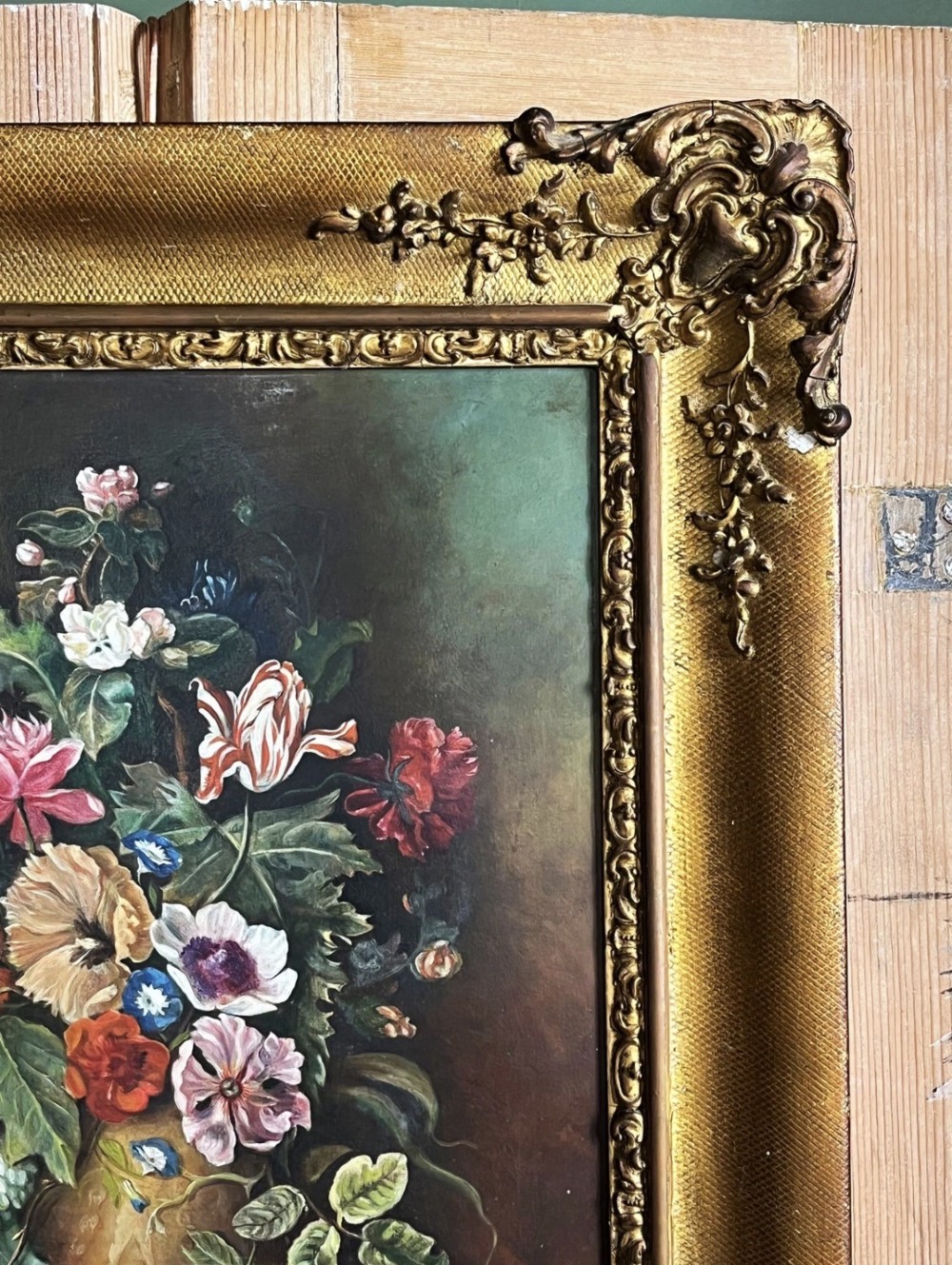 A framed oil painting depicting a floral arrangement in a urn with fruit at the base, housed within an ornate gilt gesso frame. View III