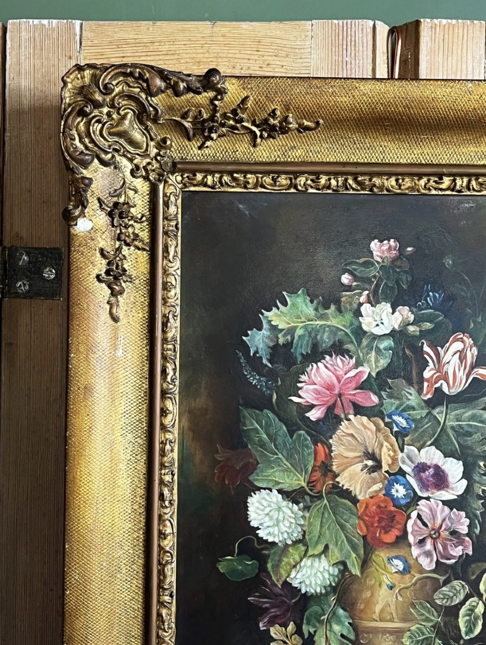 A framed oil painting depicting a floral arrangement in a urn with fruit at the base, housed within an ornate gilt gesso frame. View IV