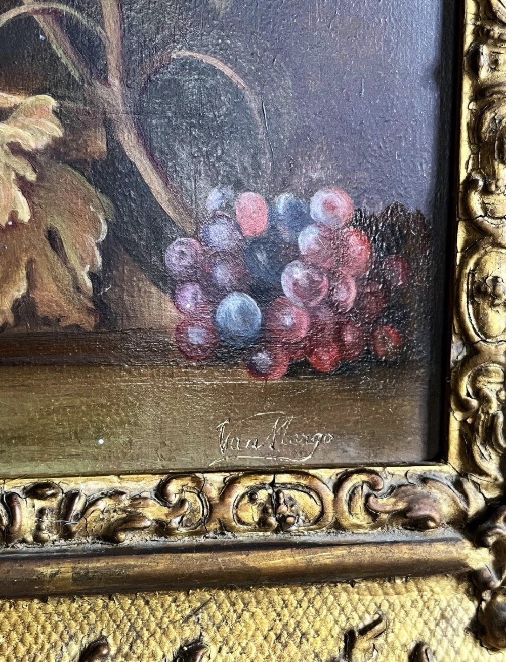 A framed oil painting depicting a floral arrangement in a urn with fruit at the base, housed within an ornate gilt gesso frame. View X