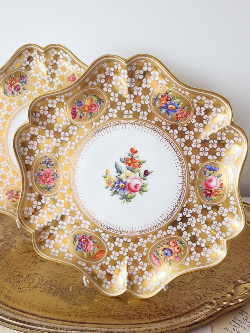 A pair of late Victorian Coalport bone china cabinet plates featuring scalloped rims heavily detailed with gold leaf, white geometric patterns, and central hand-painted floral sprays. View III