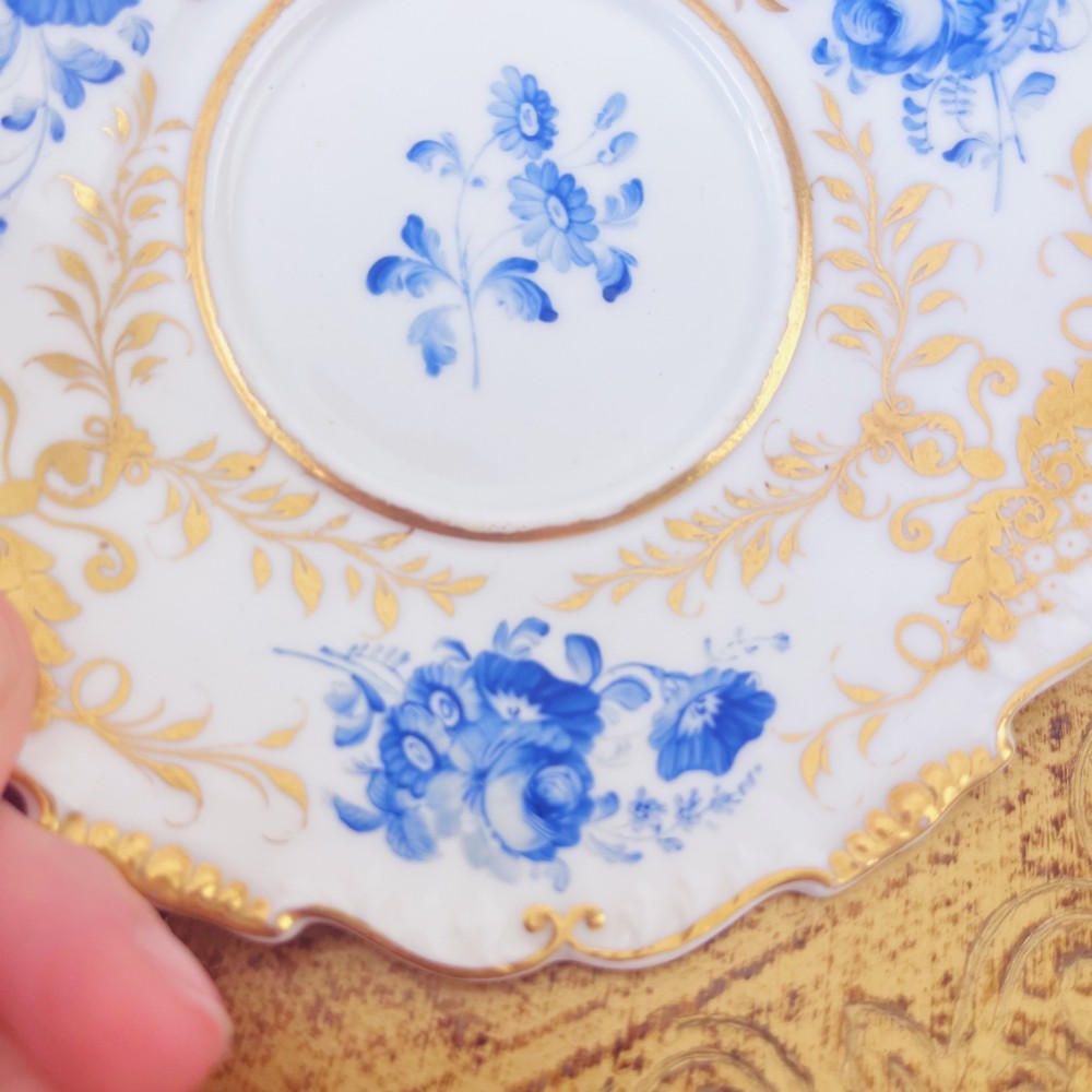 A Regency era porcelain tea trio comprising a teacup, coffee cup, and saucer decorated with blue floral hand-painting and gold leaf gilding. View XIV