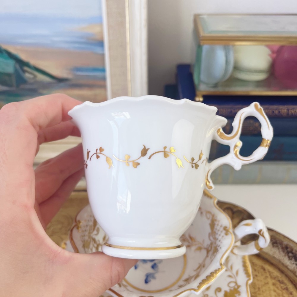 An early nineteenth-century porcelain tea and coffee cup trio featuring hand-painted blue floral motifs and gilt scroll detailing on white ground. View III