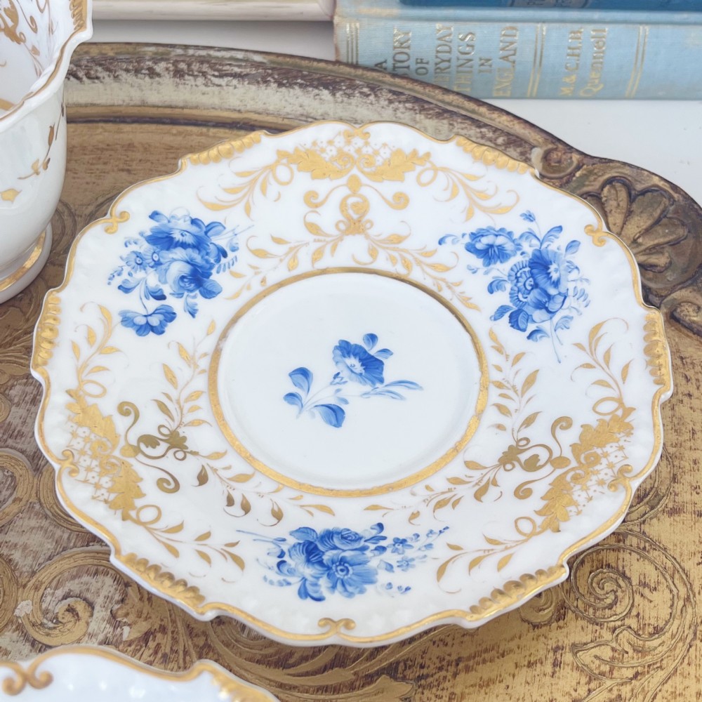 An early nineteenth-century porcelain tea and coffee cup trio featuring hand-painted blue floral motifs and gilt scroll detailing on white ground. View XI