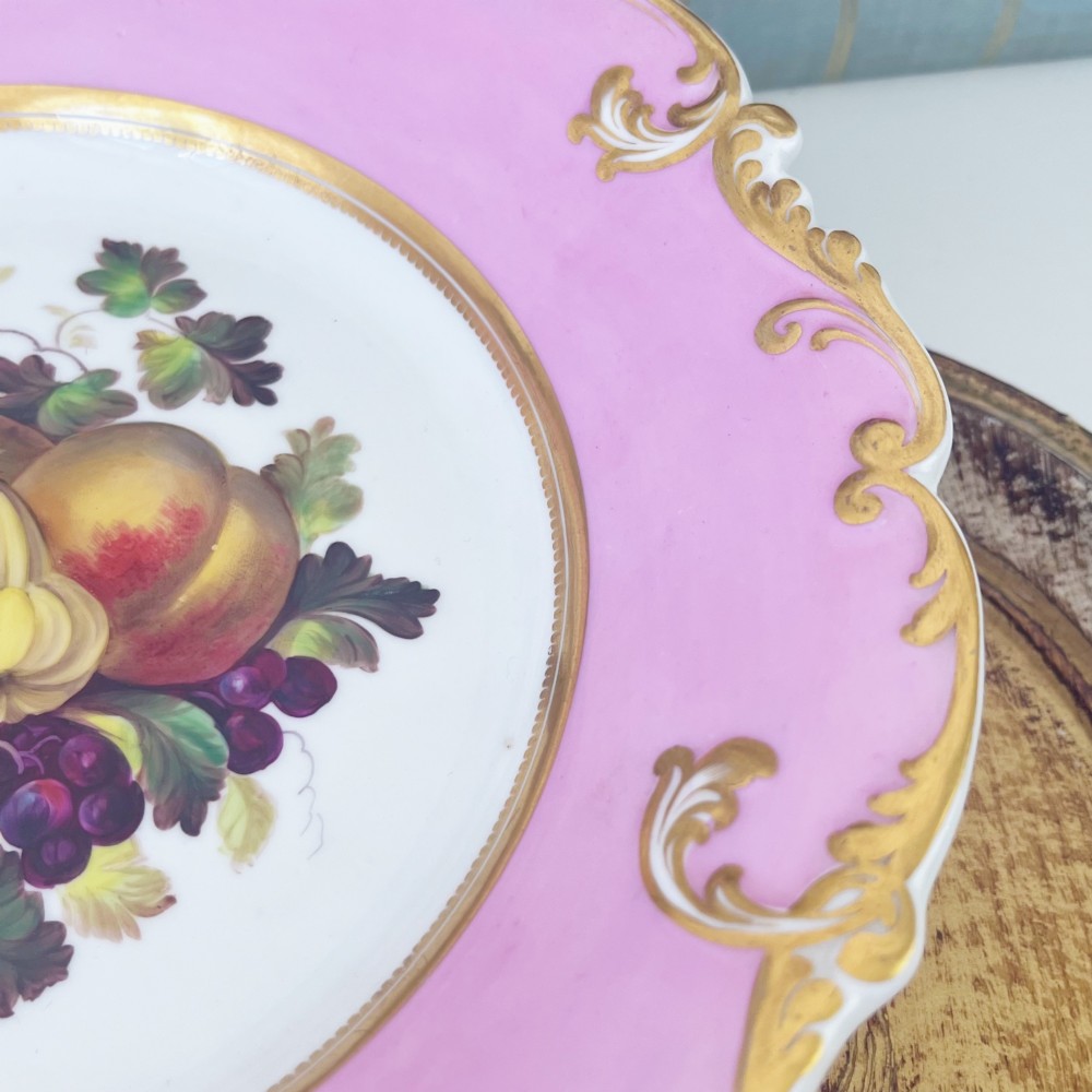 A round early nineteenth-century porcelain footed comport with a rose pink border, gilded shell edge moulding, and a hand-painted central fruit motif. View V