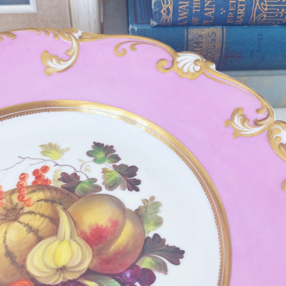 A round early nineteenth-century porcelain footed comport with a rose pink border, gilded shell edge moulding, and a hand-painted central fruit motif. View VI