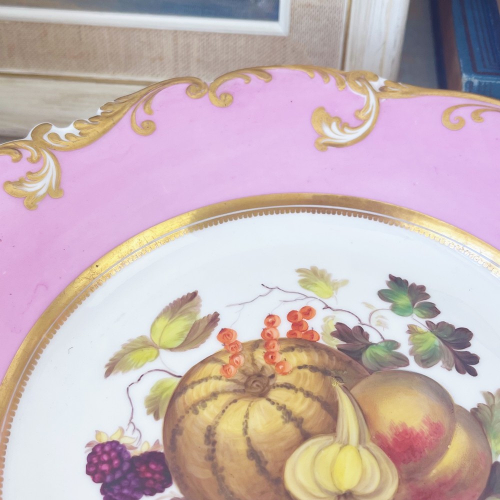 A round early nineteenth-century porcelain footed comport with a rose pink border, gilded shell edge moulding, and a hand-painted central fruit motif. View VII