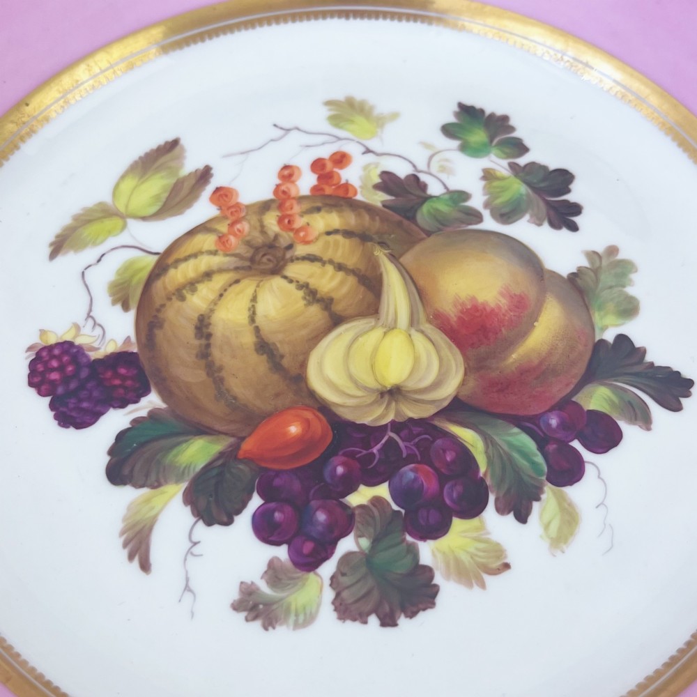 A round early nineteenth-century porcelain footed comport with a rose pink border, gilded shell edge moulding, and a hand-painted central fruit motif. View X